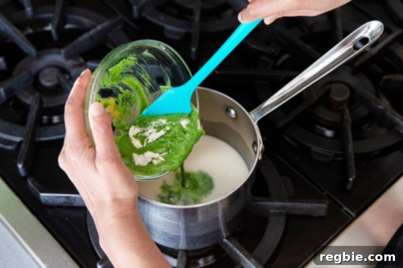 Creamy Paleo Dairy Free Matcha Pudding 7 A blue silicone spatula gently spoons the bloomed matcha and gelatin mixture into a saucepan of heated coconut milk, preparing to combine ingredients for the pudding.