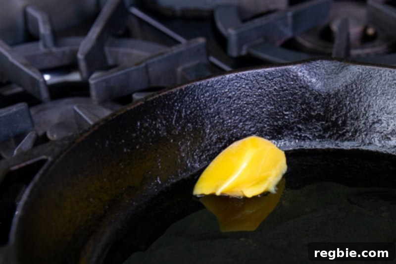 Ghee is melting in a cast iron skillet to fry paleo and keto crab cakes.