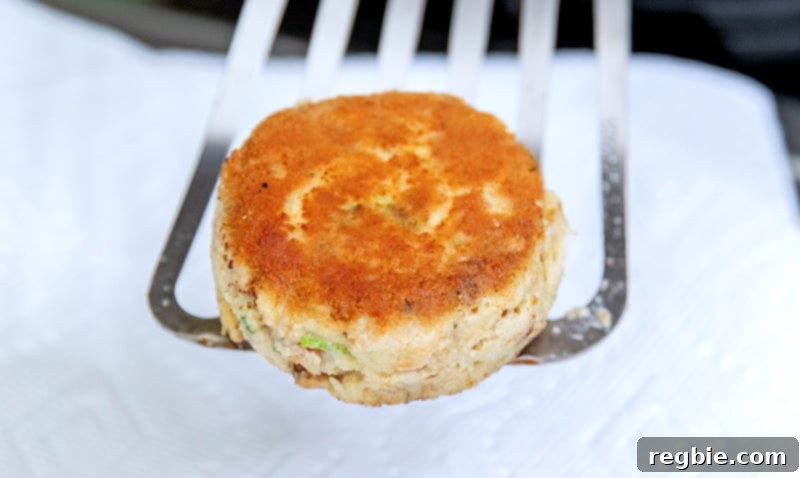 A closeup shot of a golden brown paleo and keto crab cake on a fish spatula. 