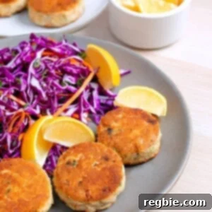 Two plates filled with paleo crab cakes, red cabbage slaw, and lemon wedges.