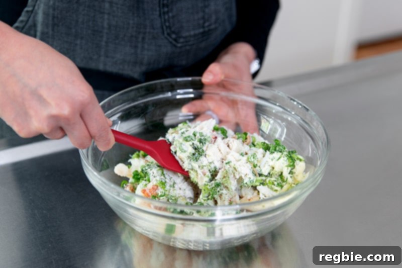 Mixing the paleo crab cake mixture with a red silicone spatula.