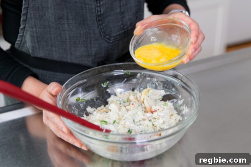 Pouring a whisked egg into the crab cake mixture.