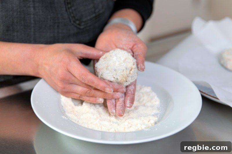 Someone coating a paleo crab cake with coconut flour.