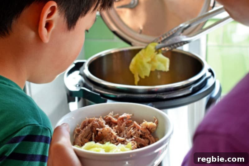 Using tongs to grab cooked cabbage out of an Instant Pot, ready to be served alongside the shredded Kalua Pork.