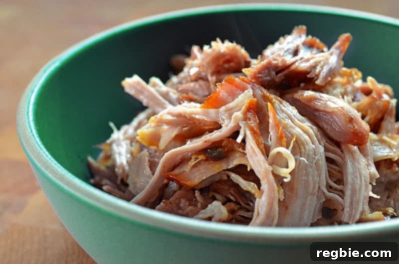 A closeup of Instant Pot (Pressure Cooker) Kalua Pig in a vibrant green serving bowl, showcasing its delicious texture.
