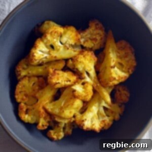 An overhead shot of a bowl of perfectly Roasted Curried Cauliflower, garnished with fresh cilantro.