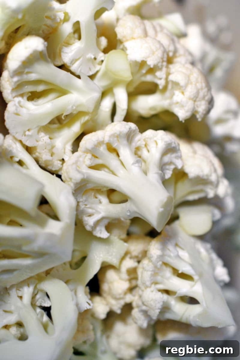 Overhead shot of raw cauliflower expertly cut into uniform florets, ready for seasoning.