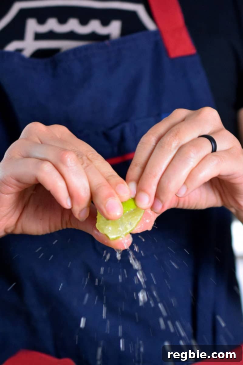 A hand gently squeezing fresh lime juice over a pile of roasted curried cauliflower.