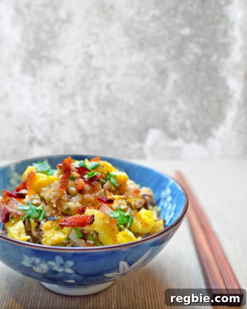 Better-Than-Takeout Asian Cauliflower Fried Rice 2 A vibrant bowl of Whole30 Asian Cauliflower Fried Rice with chopsticks