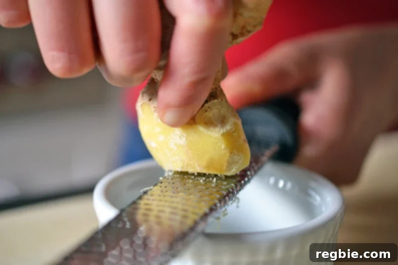 Better-Than-Takeout Asian Cauliflower Fried Rice 11 Someone grating frozen ginger on a microplane into a small ramekin, illustrating a key cooking tip