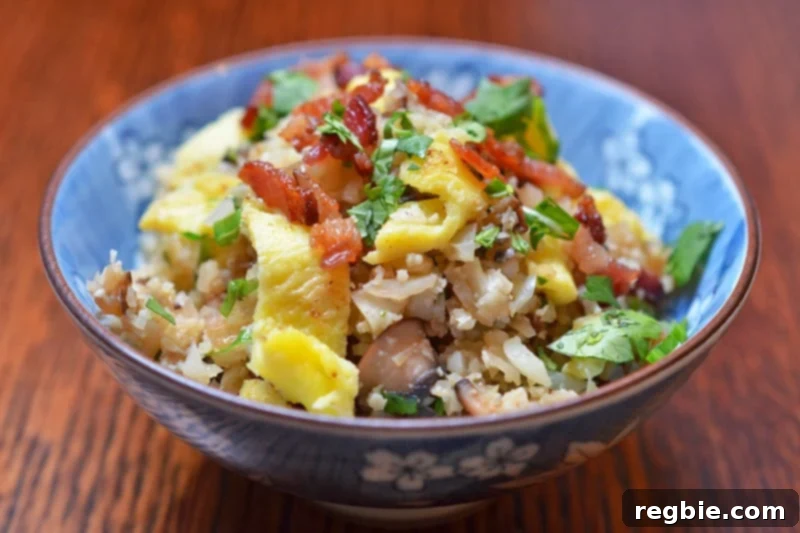 Better-Than-Takeout Asian Cauliflower Fried Rice 4 A close-up of Asian Cauliflower Fried Rice served in a blue and white bowl