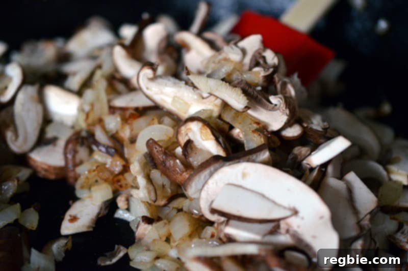 Better-Than-Takeout Asian Cauliflower Fried Rice 10 Close-up of onions and mushrooms sautéing in a hot skillet, releasing their aromas