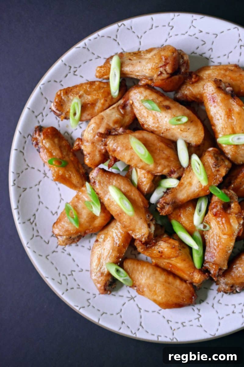 An overhead shot of a platter of baked chicken wings Magic Wings topped with sliced scallions, ready to be served for a game day or any gathering.