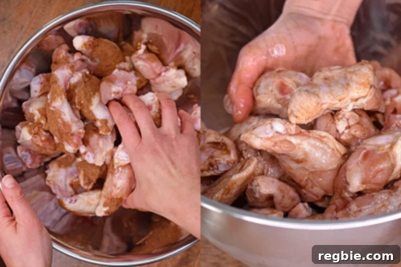 Someone tossing by hand chicken wings with marinade in a bowl, ensuring even coating before refrigeration.