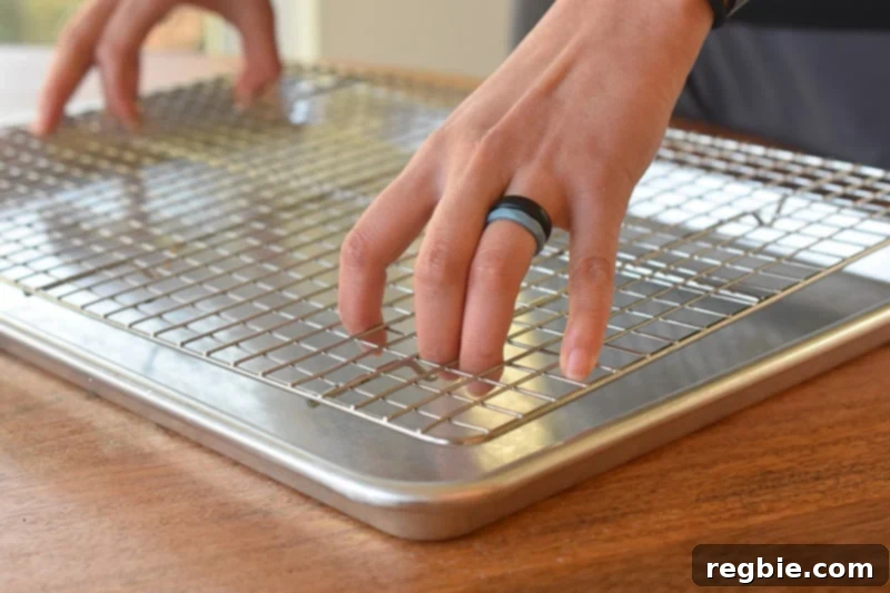 Someone placing a wire rack on top of a foil-lined baking sheet, preparing for baking crispy chicken wings.