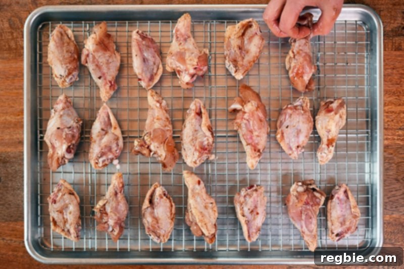 Arranged chicken wings in rows on a wire rack, perfectly spaced and ready for baking to achieve maximum crispiness.