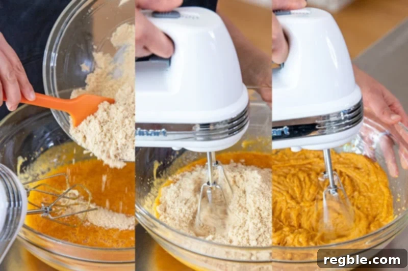 The dry ingredients are being added to the wet ingredients in a mixing bowl, followed by the use of a hand mixer to gently blend the paleo pumpkin muffin batter until smooth.