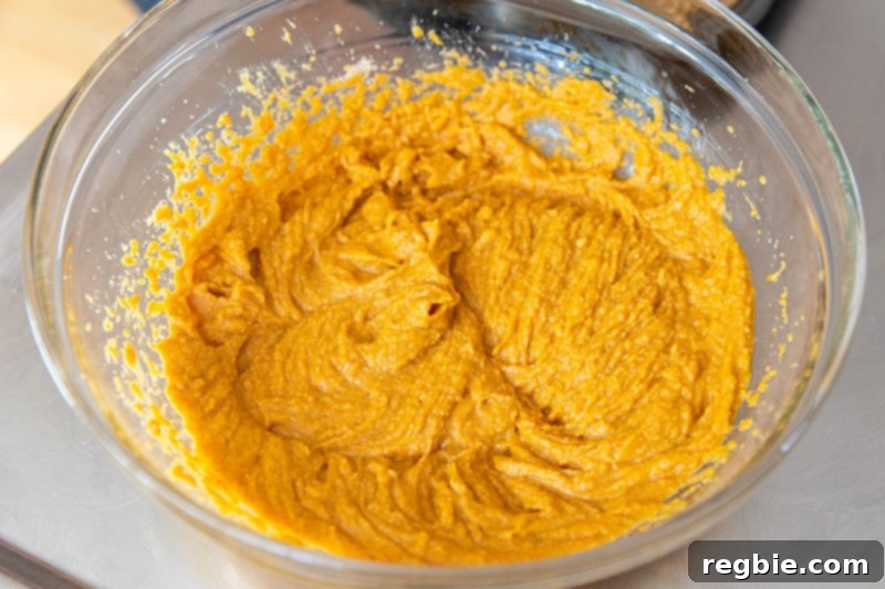 The paleo almond flour pumpkin muffin batter is shown in a bowl, perfectly mixed and ready to be scooped into the muffin tin.