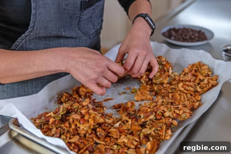 Indulgent Chocolate Cherry Granola Paleo Vegan Gluten Free 12 Someone breaking up the paleo granola into chunks after it has cooled down, preparing it for the mix-ins.