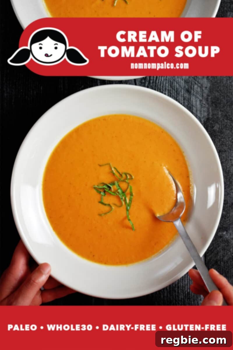 An overhead shot of a bowl of creamy dairy-free tomato soup with a spoon in it, garnished with fresh basil. A banner indicates it's paleo, Whole30, dairy-free, and gluten-free.
