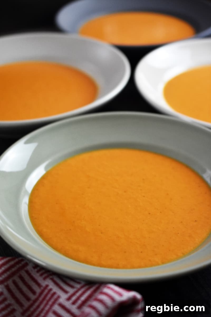 Four perfectly portioned bowls of creamy dairy-free tomato soup, ready to be enjoyed or stored.