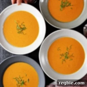 An overhead shot of four bowls filled with Whole30-friendly, paleo, and dairy-free Cream of Tomato Soup topped with basil.