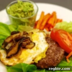 A plate with a lamb burger on top of a lettuce "bun" topped with a fried egg and sautéed shiitake mushrooms and onions.