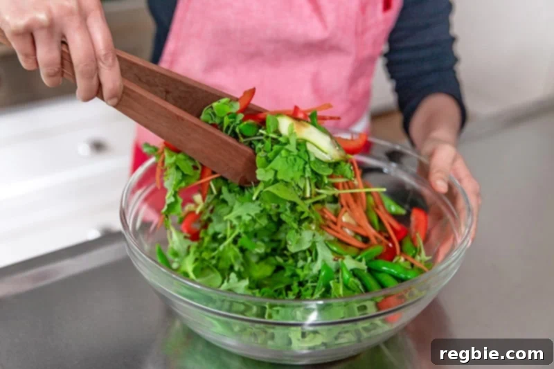 Tossing the Asian steak salad and the dressing with wooden tongs.