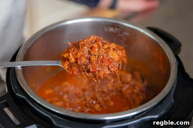 Easy Instant Pot Meat Sauce Whole30 Keto 11 A metal serving spoon is scooping out a spoonful of easy Whole30 meat sauce from an open Instant Pot
