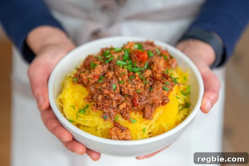Easy Instant Pot Meat Sauce Whole30 Keto 12 An overhead shot of two hands holding a bowl of spaghetti squash covered with Instant Pot meat sauce.