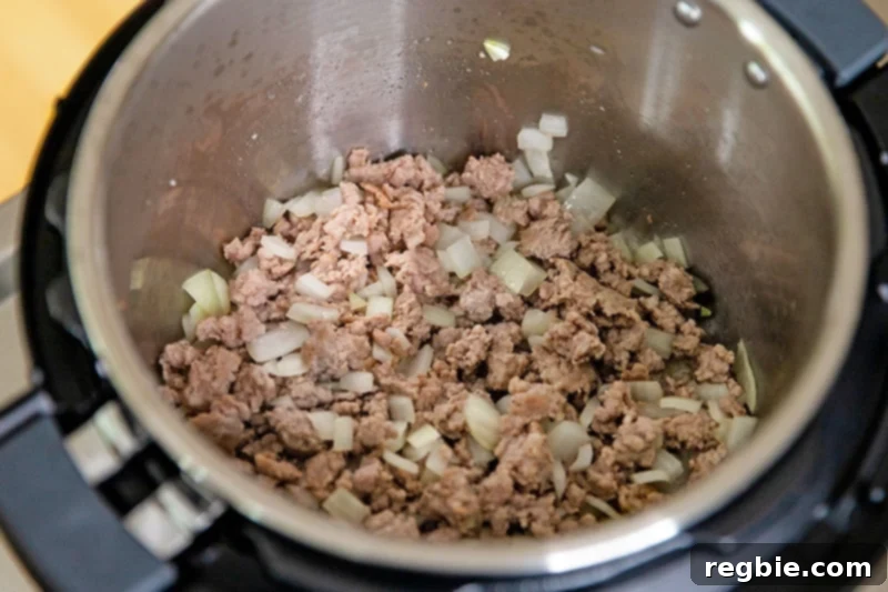 Easy Instant Pot Meat Sauce Whole30 Keto 5 An overhead shot of an open Instant Pot with cooked bulk Italian sausage and onions inside.