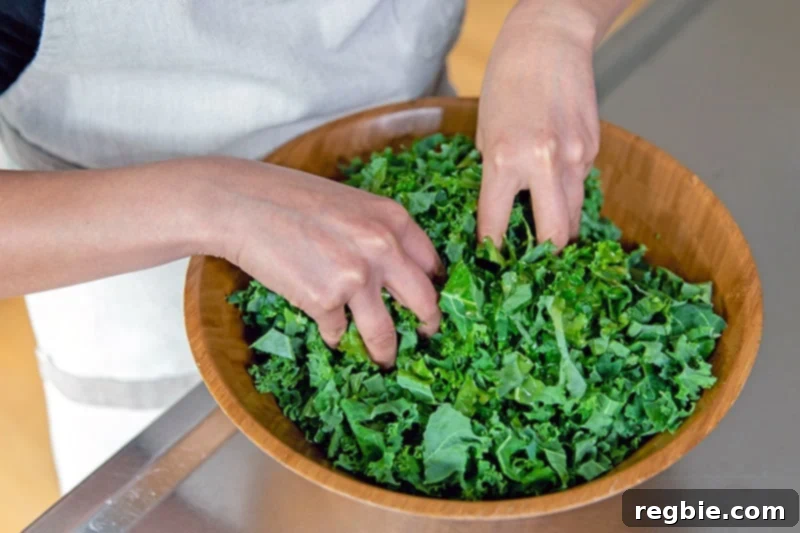 Two clean hands massaging the kale with the lemon vinaigrette.