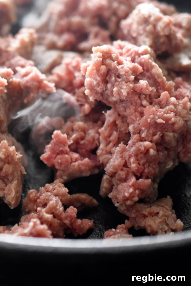 Close up shot of raw ground beef in a skillet to make Tex-Mex Beef and Cauliflower Rice Casserole.