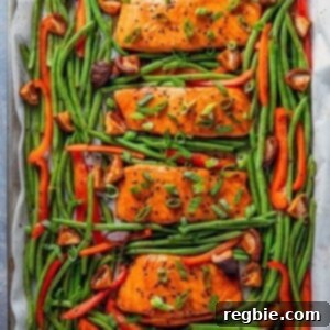 An overhead shot of Whole30 and paleo Teriyaki Salmon Sheet Pan, four cooked salmon fillets surrounded with cooked green beans and bell peppers.