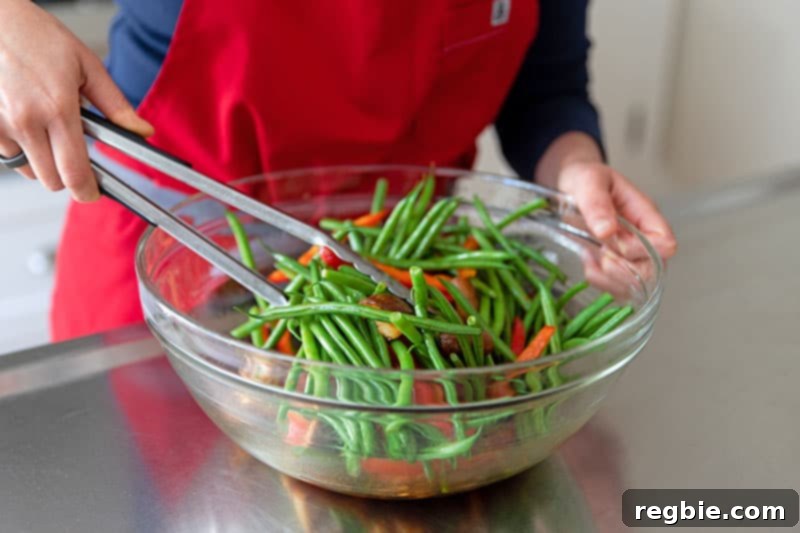 A close-up shot of fresh green beans, vibrant red bell pepper slices, and earthy shiitake mushrooms being tossed vigorously in a bowl with the Whole30 teriyaki marinade.