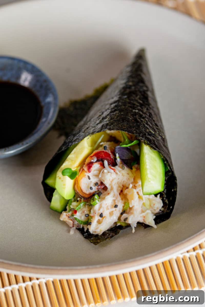 A captivating close-up of a single, delectable California hand roll presented on a stylish gray plate, accompanied by a small bowl of coconut aminos for dipping.