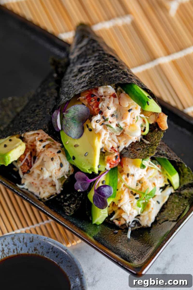 A trio of gluten-free and Whole30 California hand rolls elegantly arranged on a sleek black plate, accompanied by a small dipping bowl filled with coconut aminos.