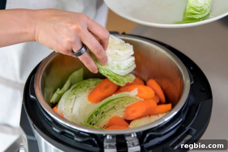 Easy Instant Pot Whole30 Keto Pork Stew 12 A hand adding cabbage wedges and sliced carrots to the Instant Pot, preparing for the final cooking stage of the Whole30 pork stew.