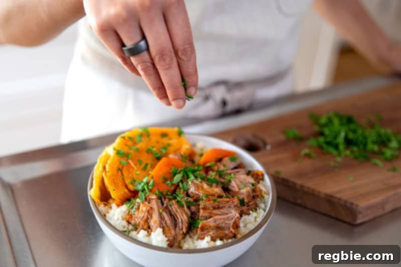 Easy Instant Pot Whole30 Keto Pork Stew 15 Someone garnishing a bowl of Instant Pot Pork and Cabbage Stew with freshly minced Italian parsley before serving.