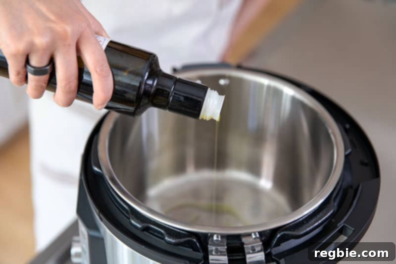 Easy Instant Pot Whole30 Keto Pork Stew 4 Someone pouring extra virgin olive oil into a hot Instant Pot on the sauté function, preparing to make the pork stew.