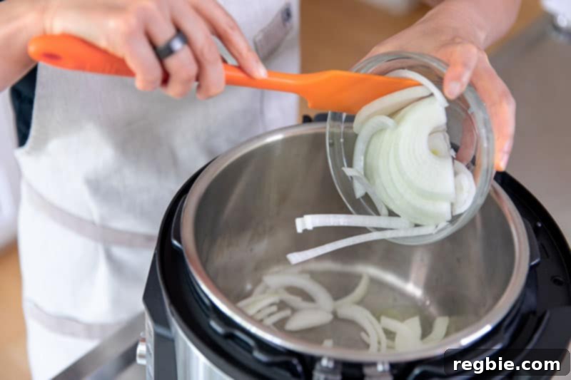 Easy Instant Pot Whole30 Keto Pork Stew 5 Adding sliced onions to the Instant Pot while on the sauté function, a crucial step for the pork and cabbage stew.