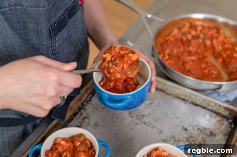 Inferno Eggs 11 Spooning a spicy sausage and mushroom tomato sauce to make Whole30 eggs in purgatory.