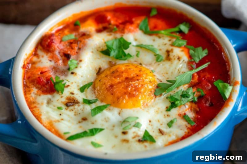 Inferno Eggs 16 A closeup shot of a blue cocotte filled with eggs in purgatory topped with minced Italian parsley.