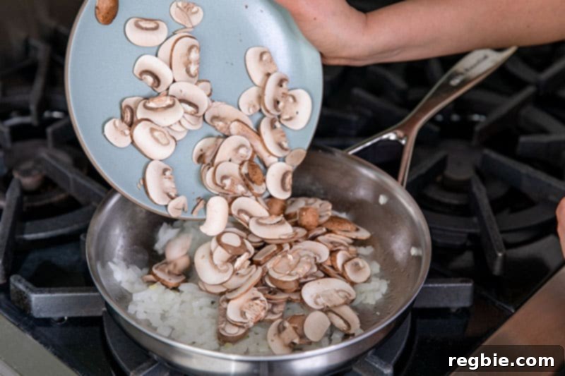 Inferno Eggs 6 Adding a plate of thinly sliced cremini mushrooms to a skillet filled with diced onions.
