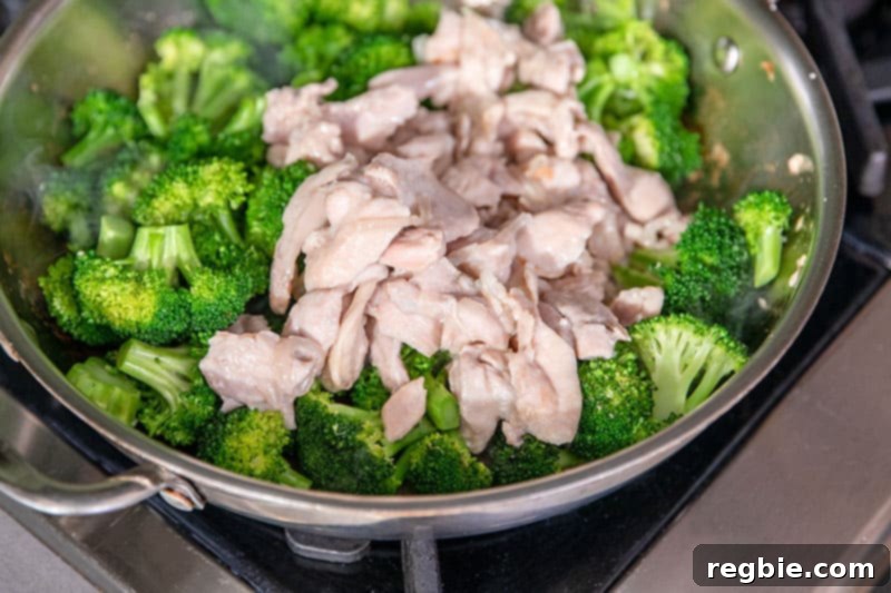 An overhead shot of a skillet filled with brightly colored, stir-fried broccoli and chicken, ready for the sauce.