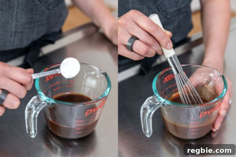 A person adding a spoonful of arrowroot powder to a liquid measuring cup filled with Nom Nom Paleo's All-Purpose Stir-Fry Sauce, preparing it for thickening.