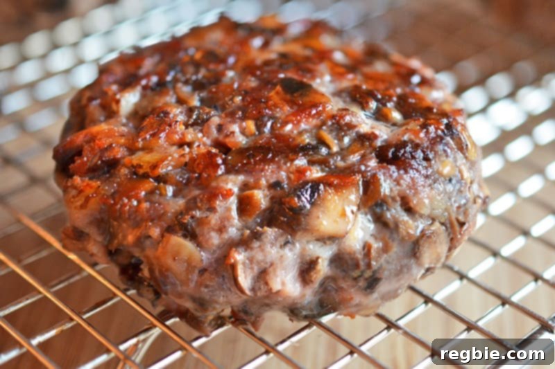 A big-o bacon burger resting on a wire rack after frying, allowing excess fat to drain.