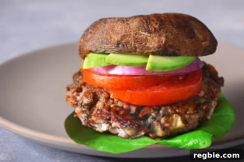 A finished big-o bacon burger on a plate, served between Portobello mushroom buns with fresh toppings.