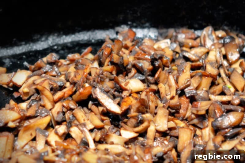 Sautéed mushrooms cooking in a cast iron skillet until moisture evaporates.
