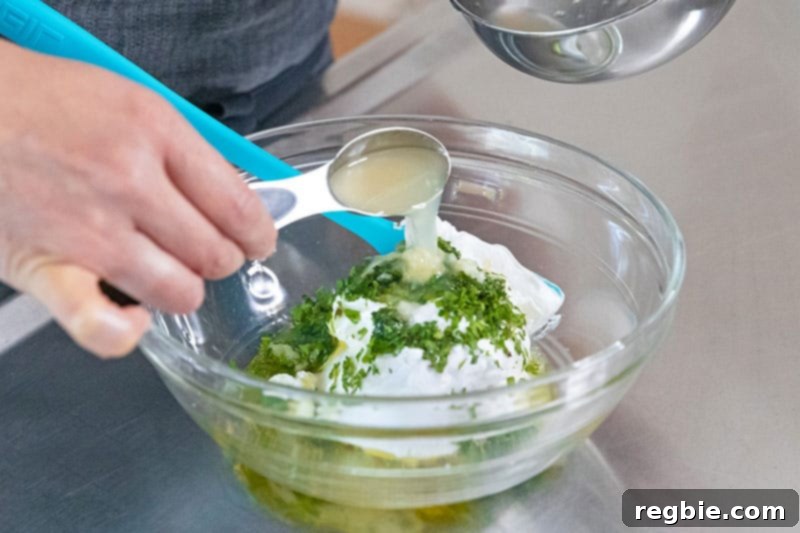 A bowl has coconut milk yogurt, herbs, diced cucumber, mint, and lemon juice to make Whole30 dairy-free tzatziki sauce.